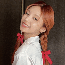 a girl with red hair is wearing a white shirt with red bows in her hair