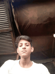 a young boy in a white shirt poses for a photo