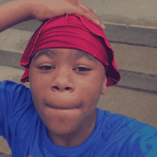 a boy wearing a blue shirt and a red headband makes a funny face