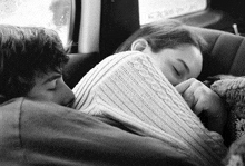 a man and a woman are sleeping in a car .