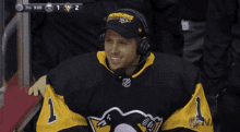 a man wearing a penguins jersey and headphones smiles