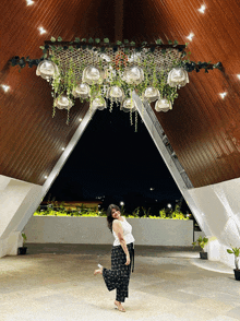 a woman stands under a ceiling with flowers and lights