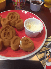 a waffle with a bite taken out of it sits on a plate next to a bowl of whipped cream