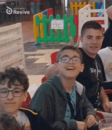 a group of young boys are sitting at a table with a sign that says made with revive on it