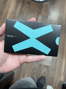 a person is holding a black box with a blue x on it