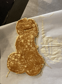 a pancake that looks like a penis is sitting on a piece of wax paper