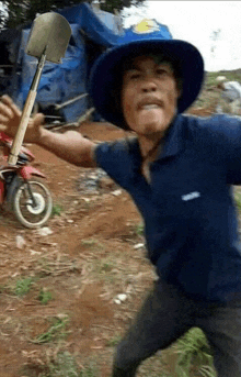 a man in a hat is holding a shovel in his hand and making a funny face .