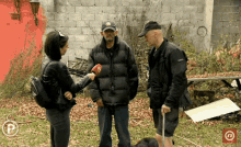 a woman is holding a microphone while talking to two men one of whom is wearing a hat with the letter n on it