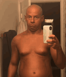 a shirtless man takes a selfie with his phone