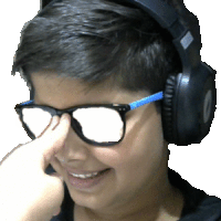 a young boy wearing glasses and headphones wipes his nose