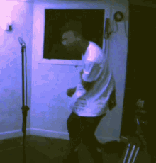 a man in a white shirt is dancing in a room with a microphone