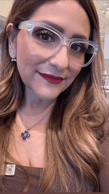 a woman wearing glasses and a necklace with a blue flower pendant