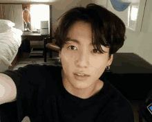 a young man is taking a selfie in a hotel room while wearing a black shirt .