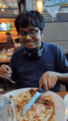 a boy wearing headphones sits at a table with a plate of food in front of a sign that says fresh march