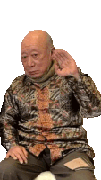 a bald man wearing a shirt with a pattern on it is covering his ears