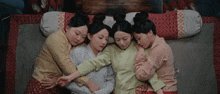 a group of women are laying on a bed .