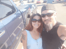 a man and a woman pose for a picture in front of a blue truck