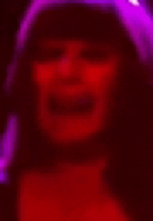 a blurry picture of a woman 's face in a dark room with purple lights .