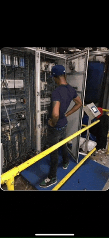 a man in a blue shirt is standing in front of a large electrical box .