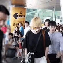 a group of people are walking down a street in front of a sign that says ' seoul ' on it .