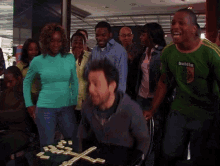 a group of people standing around a table with dominoes and a man wearing a green shirt that says dublin