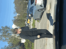 a man standing on a sidewalk next to a parked car