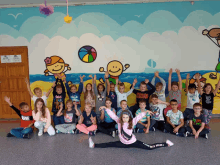 a group of children are posing for a picture in front of a wall with cartoons on it including one that says love