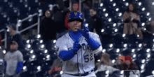 a baseball player in a blue and white uniform is standing in front of a crowd at a baseball game .