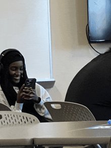 a woman wearing headphones looks at her cell phone