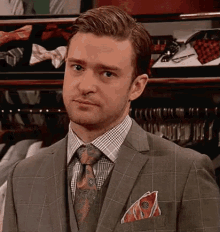 a man in a suit and tie is standing in front of a display of bow ties in a store .