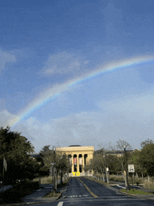 a street with a rainbow in the sky and a sign that says speed limit 25