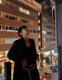 a man in a black jacket stands in front of a building with a sign that says ' ao ' on it