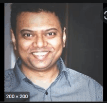 a man in a blue shirt is smiling and looking at the camera in a black and white photo .