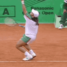 a tennis player is jumping in the air while holding a tennis racquet in front of a panasonic open sign