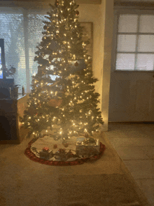 a christmas tree is lit up in a living room with gifts underneath it