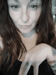 a woman with a tattoo on her finger is making a face .