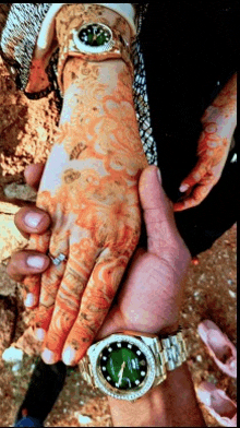 a man wearing a watch with a green face holds a woman 's hand