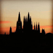 a silhouette of a cathedral at sunset with a sunset sky in the background