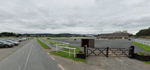 a lot of cars are parked on the side of the road near a fence