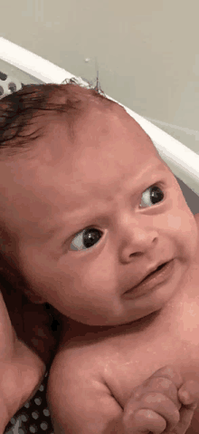 a baby is laying in a bathtub and making a funny face