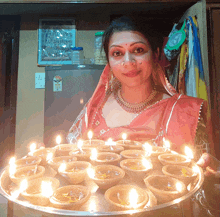 a woman in a red dress holds a tray of lit candles in front of a refrigerator that has a sticker on it