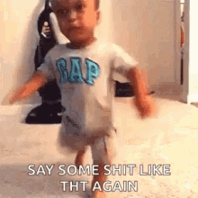 a little boy wearing a gap shirt is walking on the floor .