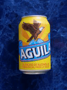 a can of aguila beer is sitting on a blue surface .