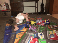 a child laying on a rug playing with toys and a box that says nox