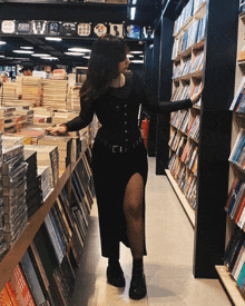 a woman in a black dress is standing in a book store looking at books