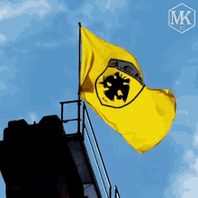 a yellow flag with a black eagle and the letter ak on it