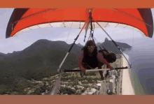 a person is flying through the air on a parachute with mountains in the background