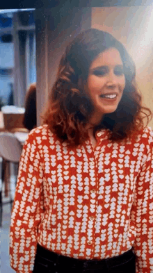 a woman is wearing a red and white shirt with hearts on it