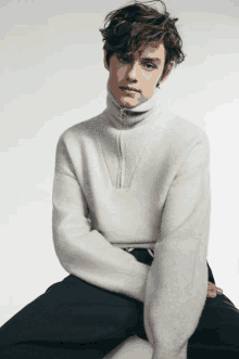 a young man wearing a white sweater with a zipper on the front