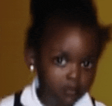 a close up of a little girl 's face wearing a white shirt and pearl earrings .